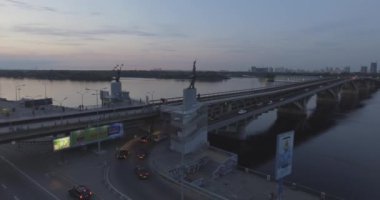 Hava. Ukrayna şehir Kiev. Metro Dnieper İstasyonu'na varış. 2017.06.09. metro Dnieper Nehri Köprüsü. Yaz alacakaranlık, köprü Idol Dnepr metro Köprüsü yukarıdaki arabaları.