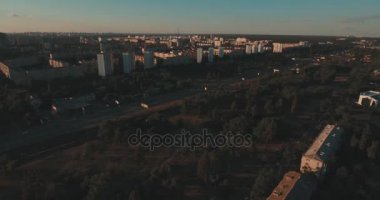 Hava, cadde ve gündoğumu, yüksek binalar. Yaz sabah cityscape üzerinden bir kuş bakışı. Metropol üzerinde uçuş. Güneşli sabah, mavi gökyüzü. Bir sürü yeşil ağaç sokaklarda.