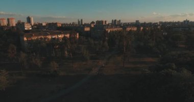 Hava, cadde ve gündoğumu, yüksek binalar. Yaz sabah cityscape üzerinden bir kuş bakışı. Metropol üzerinde uçuş. Güneşli sabah, mavi gökyüzü. Bir sürü yeşil ağaç sokaklarda.
