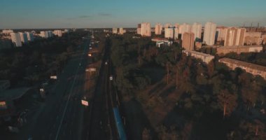 Hava, cadde ve gündoğumu, yüksek binalar. Yaz sabah cityscape üzerinden bir kuş bakışı. Metropol üzerinde uçuş. Güneşli sabah, mavi gökyüzü. Bir sürü yeşil ağaç sokaklarda.