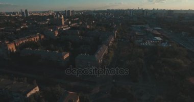 Hava, cadde ve gündoğumu, yüksek binalar. Yaz sabah cityscape üzerinden bir kuş bakışı. Metropol üzerinde uçuş. Güneşli sabah, mavi gökyüzü. Bir sürü yeşil ağaç sokaklarda.