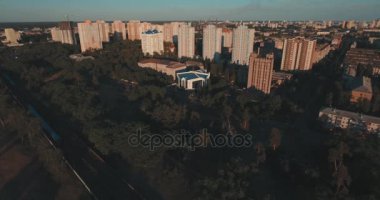 Hava, cadde ve gündoğumu, yüksek binalar. Yaz sabah cityscape üzerinden bir kuş bakışı. Metropol üzerinde uçuş. Güneşli sabah, mavi gökyüzü. Bir sürü yeşil ağaç sokaklarda.