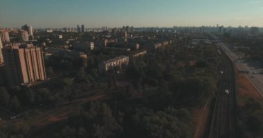 Hava, cadde ve gündoğumu, yüksek binalar. Yaz sabah cityscape üzerinden bir kuş bakışı. Metropol üzerinde uçuş. Güneşli sabah, mavi gökyüzü. Bir sürü yeşil ağaç sokaklarda.