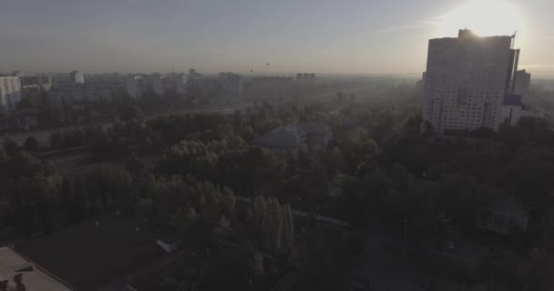 日の出高層建物の航空写真 鳥の目のビューから夏の朝の街並み 大都市以上のフライト 晴れた朝 青い空 路上では緑の木々 の多く — ストック動画