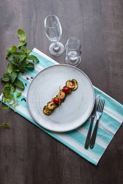 Shrimps, zucchinis and cherry tomatoes in white plate above the Stock Photo