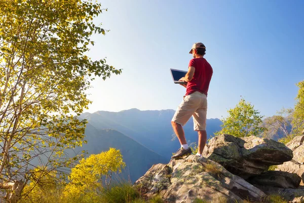 Mann steht auf Felsen und arbeitet am Laptop — Stockfoto