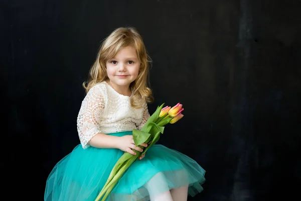 Menina bonita com tulipas em um fundo preto — Fotografia de Stock