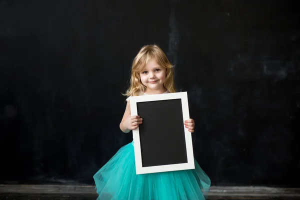 Roztomilá holčička s rámečkem, který ve svých rukou — Stock fotografie