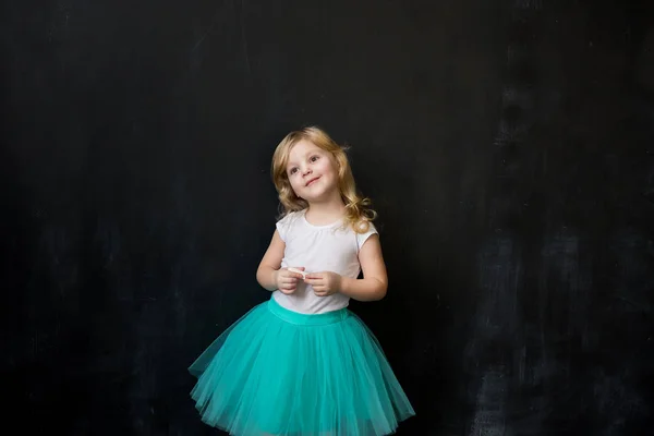 Young girl standing in front of chalk board — Stock Photo, Image