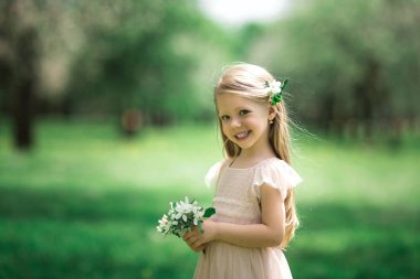 Küçük kız bir elma bahçesinde yürüyor