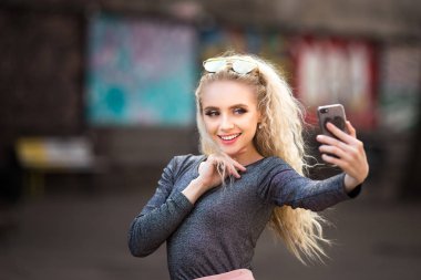 Genç gülümseyen neşeli sarışın kız dururken selfie yapma 