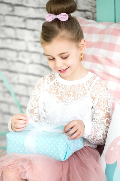 Menina bonito abre um presente de aniversário — Fotografia de Stock