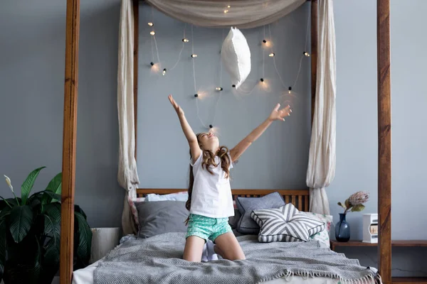 Menina brincando na cama no quarto — Fotografia de Stock