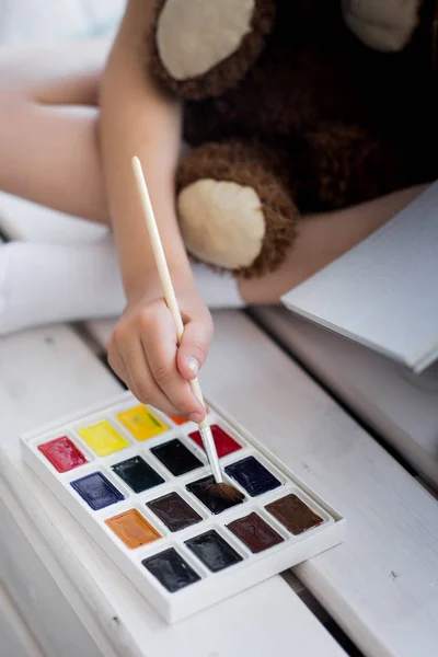 Beautiful little girl draws paints on the window — Stock Photo, Image