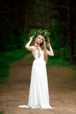 Beyaz bir elbise ve F çelenk içinde güzel bir gelin portresi