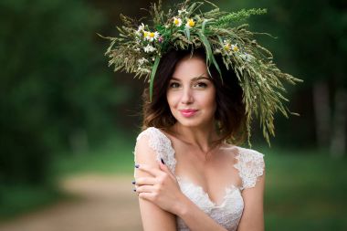 Beyaz bir elbise ve F çelenk içinde güzel bir gelin portresi