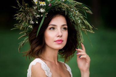 Beyaz bir elbise ve F çelenk içinde güzel bir gelin portresi