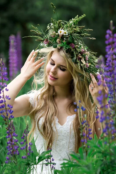 Mooi meisje in een witte jurk in lupine veld — Stockfoto