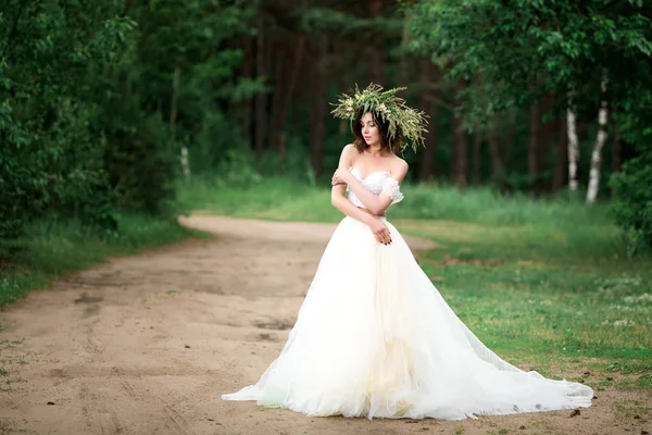 Bella sposa in un abito bianco con una corona di fiori — Foto Stock