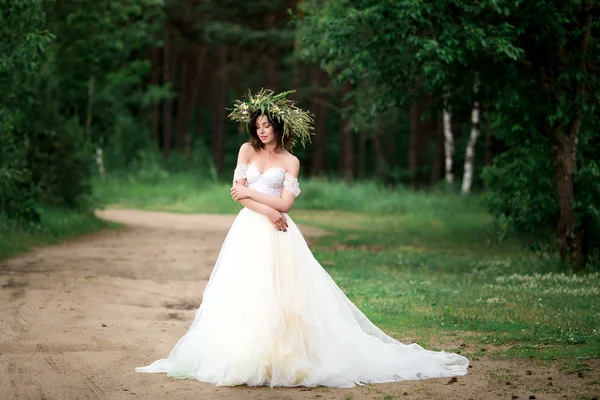 Bella sposa in un abito bianco con una corona di fiori — Foto Stock