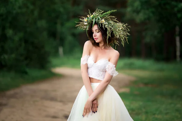 Schöne Braut in einem weißen Kleid mit einem Blumenkranz — Stockfoto