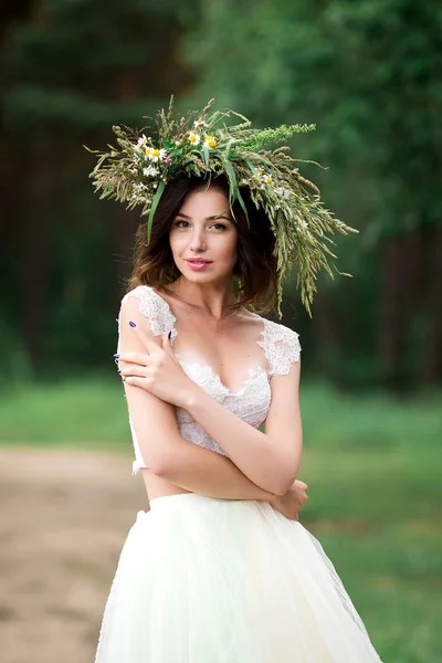 Bela noiva em um vestido branco com uma coroa de flores — Fotografia de Stock