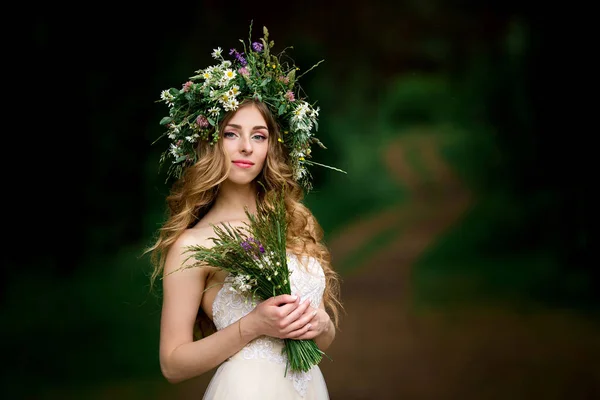 Bella sposa in un abito bianco con una corona di fiori — Foto Stock