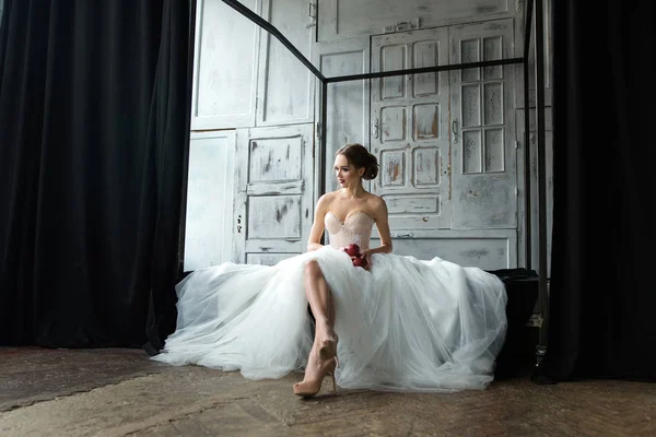 Krásná nevěsta s světlý make-up sedí na posteli — Stock fotografie