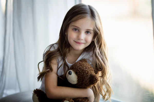 Retrato de una hermosa chica con un oso de juguete marrón — Foto de Stock