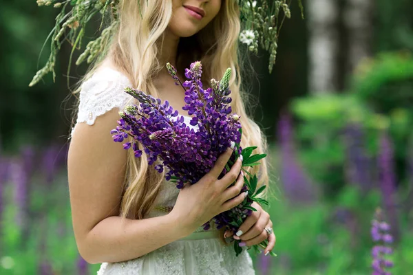 Mooi meisje in een witte jurk in lupine veld — Stockfoto