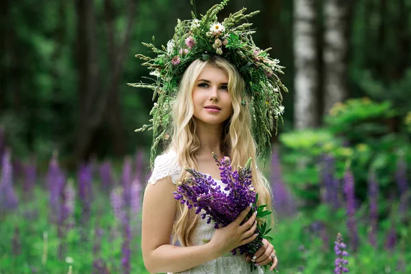 Mooi meisje in een witte jurk in lupine veld — Stockfoto