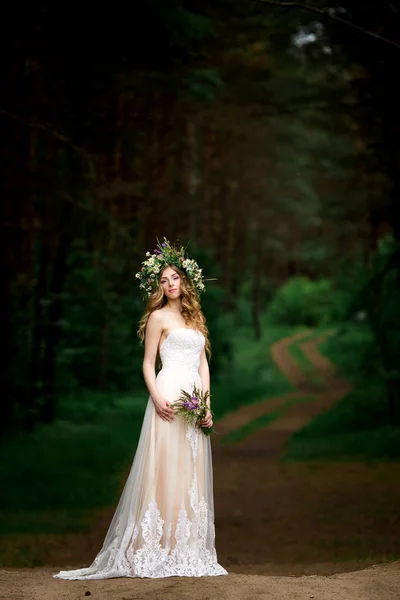 Bela noiva em um vestido branco com uma coroa de flores — Fotografia de Stock