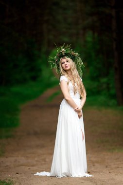 Beyaz bir elbise ve F çelenk içinde güzel bir gelin portresi