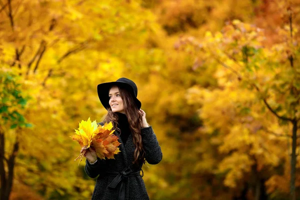 Donna con foglie autunnali in mano e acero giallo autunno giardino sfondo — Foto Stock