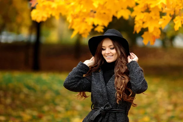 Wanita dengan daun musim gugur di tangan dan jatuh kuning maple taman latar — Stok Foto