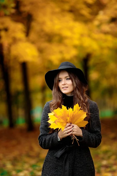 Donna con foglie autunnali in mano e acero giallo autunno giardino sfondo — Foto Stock