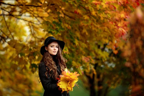 Jovem mulher com folhas de outono na mão e queda amarelo bordo jardim fundo — Fotografia de Stock