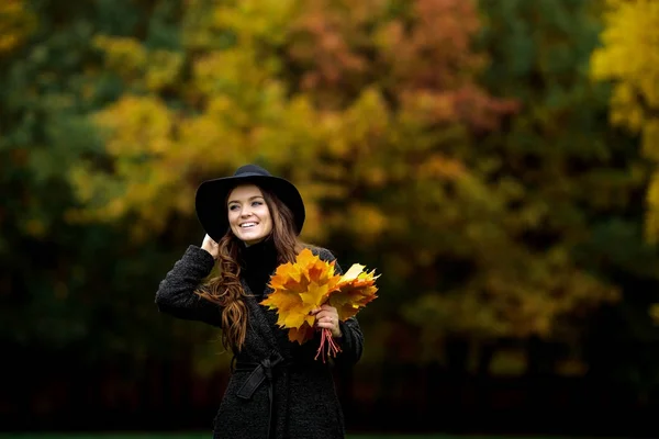 Mujer con hojas de otoño en la mano y caída de arce amarillo fondo del jardín —  Fotos de Stock