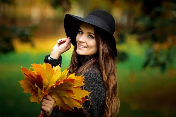 Mujer con hojas de otoño en la mano y caída de arce amarillo fondo del jardín —  Fotos de Stock