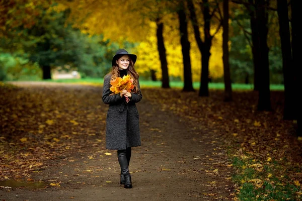 Mulher com folhas de outono na mão e queda amarelo bordo jardim fundo — Fotografia de Stock