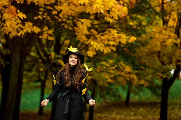 Donna con foglie autunnali in mano e acero giallo autunno giardino sfondo — Foto Stock