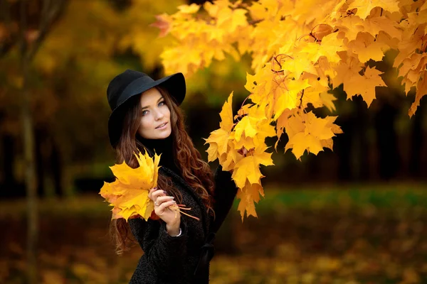 Mulher com folhas de outono na mão e queda amarelo bordo jardim fundo — Fotografia de Stock