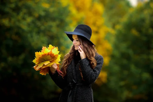 Donna con foglie autunnali in mano e acero giallo autunno giardino sfondo — Foto Stock