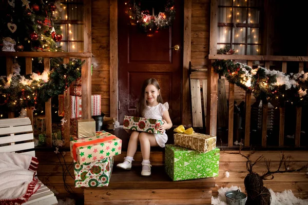 Маленькая улыбающаяся девочка с рождественской подарочной коробкой . — стоковое фото
