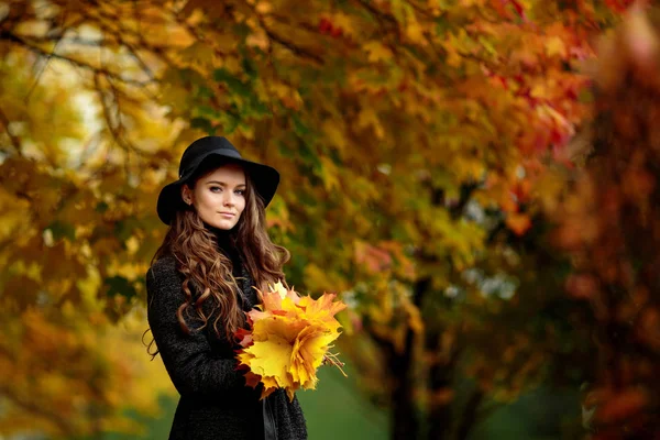 Woman with autumn leaves in hand and fall yellow maple garden background — Stock Photo, Image