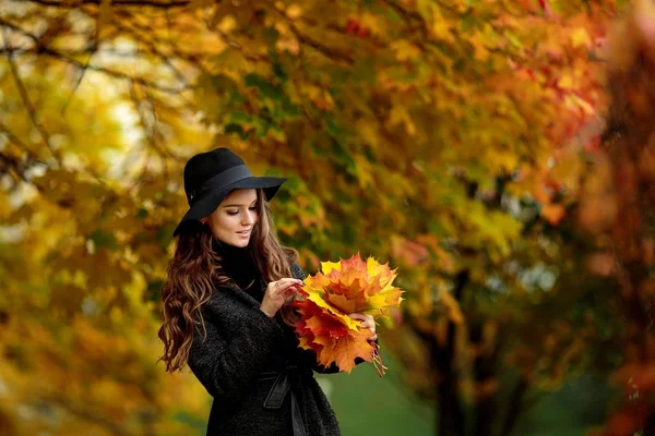 Mulher com folhas de outono na mão e queda amarelo bordo jardim fundo — Fotografia de Stock