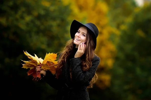 Mulher com folhas de outono na mão e queda amarelo bordo jardim fundo — Fotografia de Stock