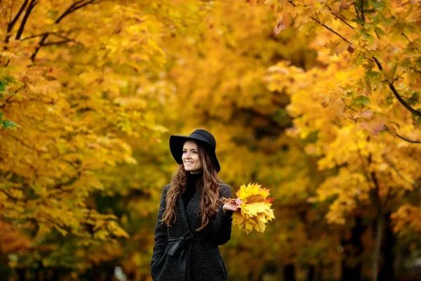 Женщина с осенними листьями в руке и осенью желтый кленовый сад фон — стоковое фото