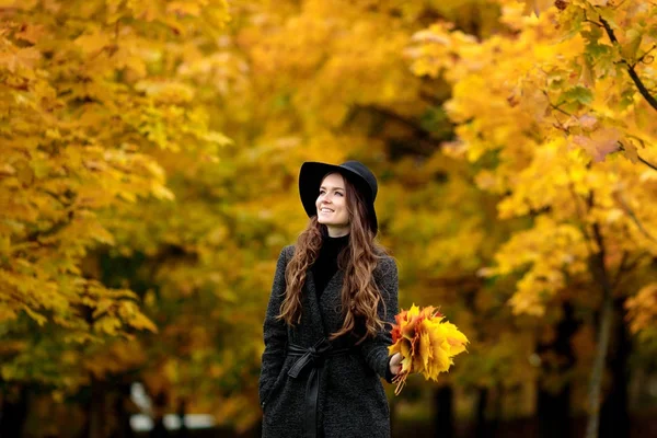 Mujer con hojas de otoño en la mano y caída de arce amarillo fondo del jardín —  Fotos de Stock