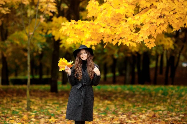 Happy young woman in a hat in an autumn park — Stock Photo, Image